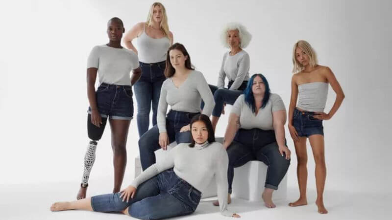 Foto que representa a diversidade, com diversas modelos de diferentes cores e formatos de corpo em frente a um fundo branco